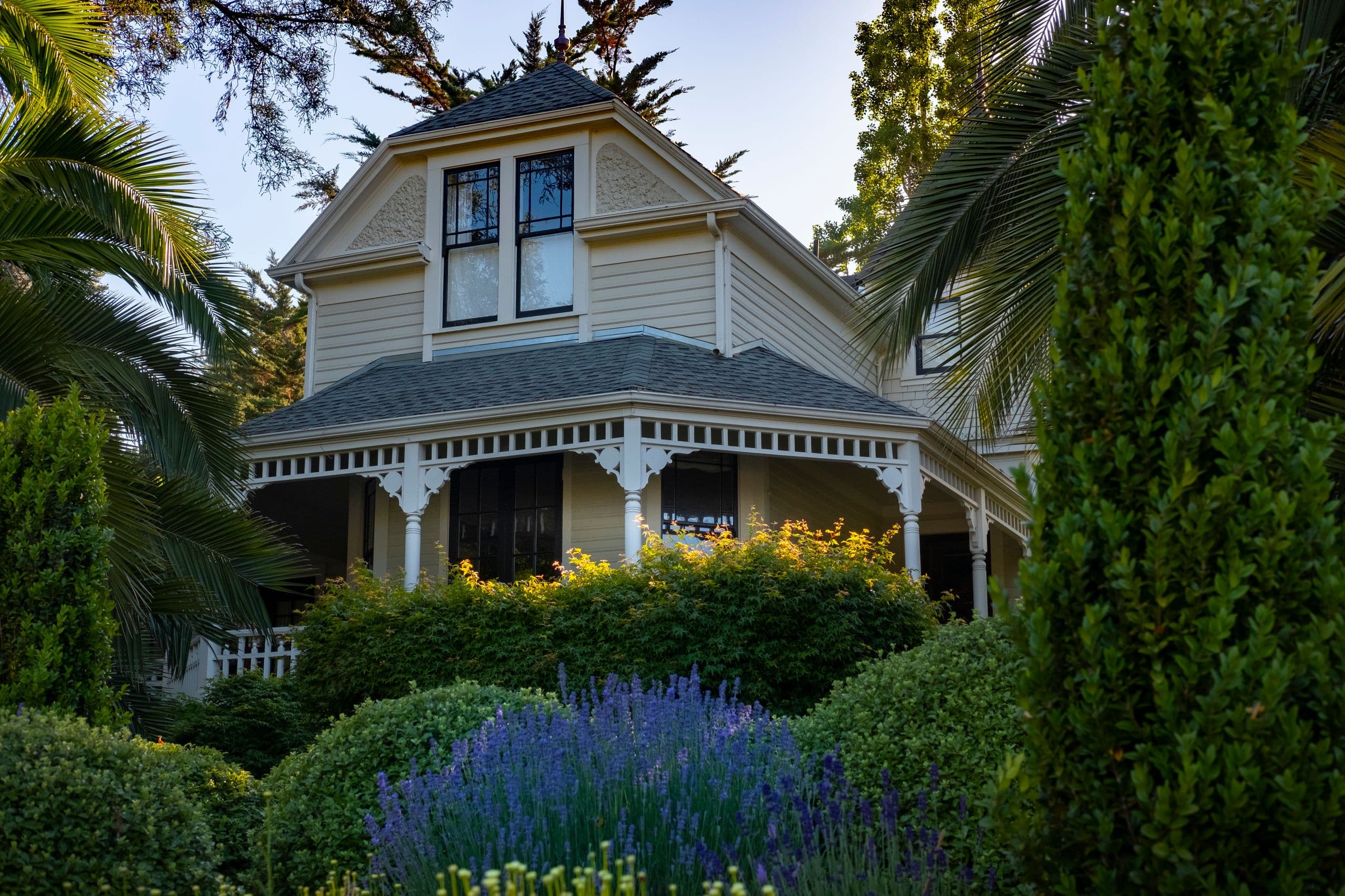 A Victorian home behind a garden in full bloom
