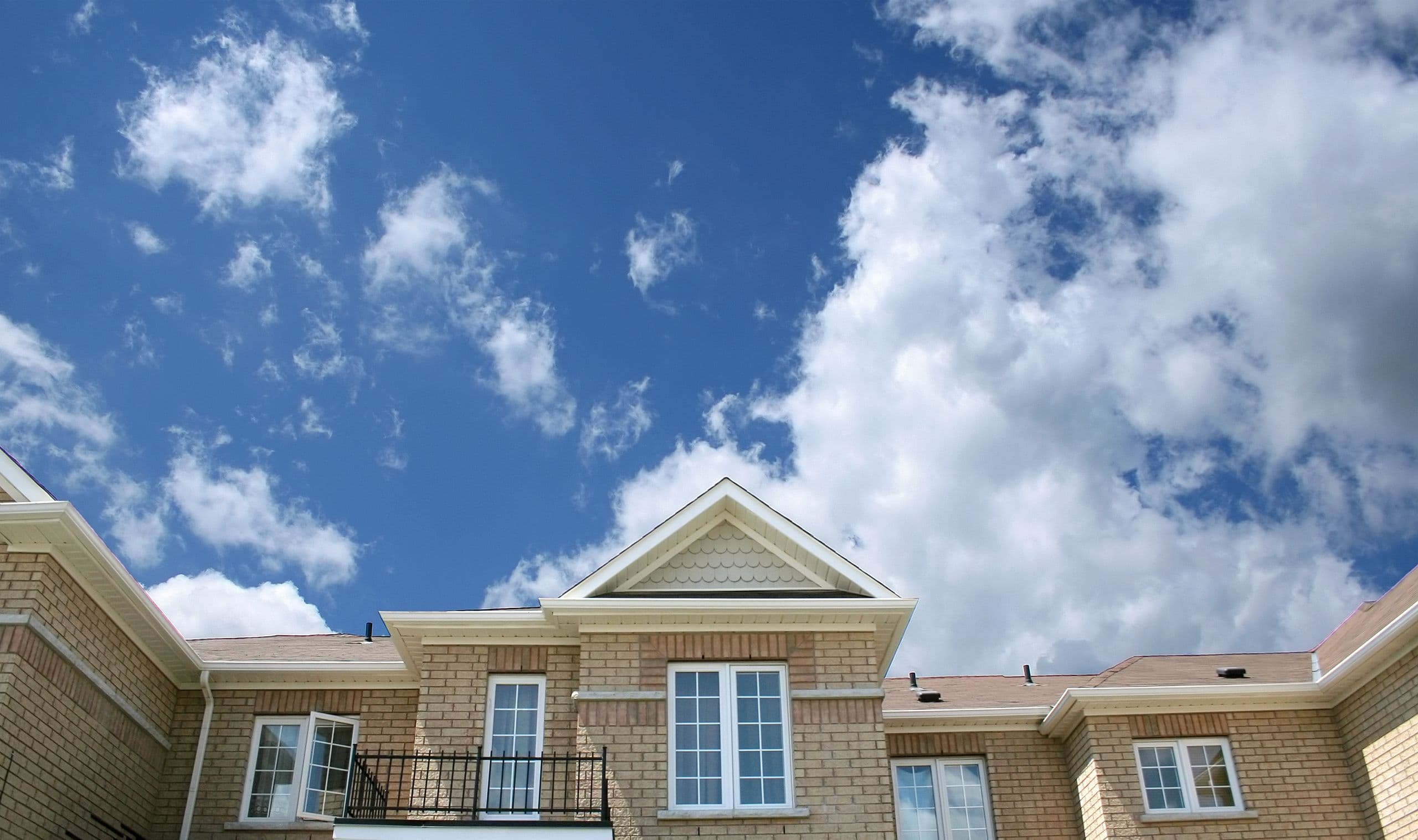 Brick homes against a bright sky